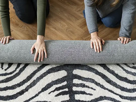 friends rolling up rug to rotate 