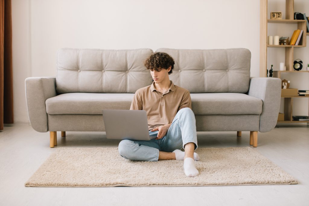 man using a sofa while sitting on a carpet