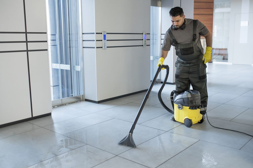 man cleaning tiles with a vacuum cleaner